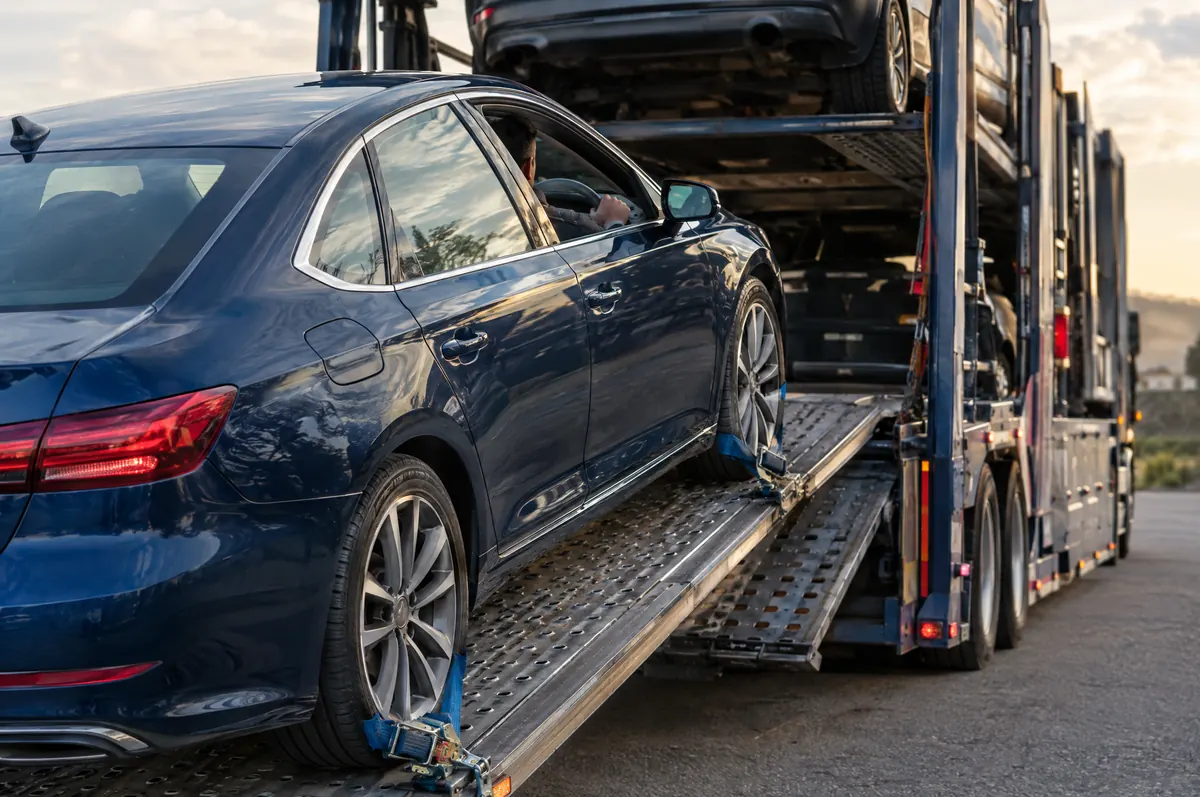Sedan being loaded up the ramp of an open car carrier